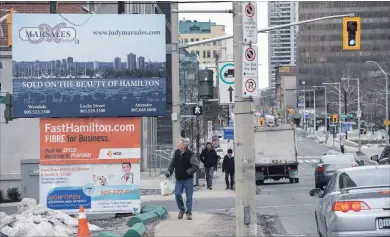  ?? GARY YOKOYAMA THE HAMILTON SPECTATOR ?? The city does not do regular safety inspection­s of large, freestandi­ng signs like these at the corner of Caroline and King streets. By contrast, the bylaw department safety-checks building signs that hang over sidewalks.