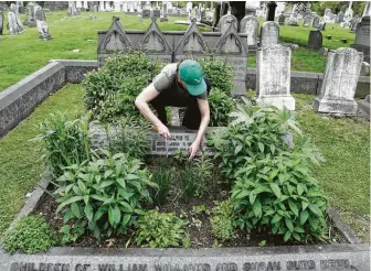  ?? Jacqueline Larma / Associated Press ?? Volunteer Jennifer Walker clears an area as she plants on the Keen family plot at The Woodlands Cemetery in Philadelph­ia. The cemetery has restored the bygone tradition of cemetery gardening.