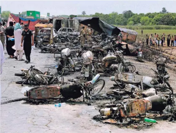  ?? AP ?? Vehículos calcinados, además de cadáveres, quedaron en el lugar donde explotó el camión cisterna, en una carretera cerca de Bahawalpur.
