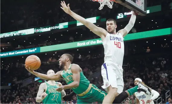  ?? AP FOTO ?? ACROBATIC SHOT. Boston Celtics Kemba Walker (8) tries to get past Los Angeles Clippers center Ivica Zubac (40) .