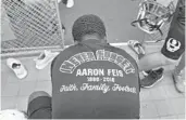  ?? JIM RASSOL/STAFF FILE ?? Kenny Kernizan of the Marjory Stoneman Douglas High football team gets ready in April for the first day of spring practice wearing the “Never Forget” T-shirt honoring coach Aaron Feis, left.