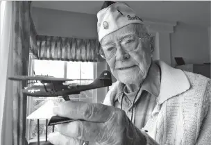  ??  ?? Retired U.S. Navy Cmdr. Don Long on Friday holds up a replica of the military seaplane he was standing watch on when Japanese warplanes attacked Hawaii in 1941.