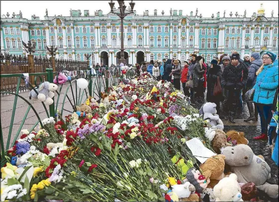  ?? AP ?? Russians visit a makeshift memorial for the plane crash victims in St. Petersburg Wednesday. According to a US official, they have intelligen­ce reports that someone at the airport assisted a terrorist to plant a bomb on the Russian Metrojet plane.