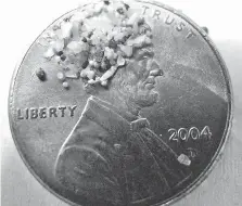  ??  ?? Plastic microbeads, seen here compared to a penny for size, have been used in many bath and hair products. They end up polluting lakes.