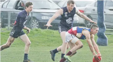  ??  ?? Warragul Industrial­s’ player Will Jolley gathers the loose ball as his Catani opponents move in to apply pressure.