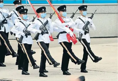  ?? PETER PARKS / AFP ?? Oficiales de policía de Hong Kong marchan al paso de la oca con la bandera china y la de la ciudad