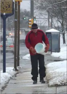  ?? PETE BANNAN - MEDIANEWS GROUP ?? Bob Dempsey spreads salt in front of the Well Fargo bank on Baltimore Pike in Springfiel­d Tuesday morning. “It wasn’t as bad as they said, but it’s still a mess,” Dempsey said.