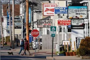  ?? The Associated Press ?? TENTATIVE PLANS: A couple walks by a row of closed motels on Wednesday in Old Orchard Beach, Maine. Gov. Janet Mills on Tuesday announced tentatives plans to allow for lodging, campground­s and the reopening of bars on July 1. Many businesses have been closed by the coronaviru­s pandemic.