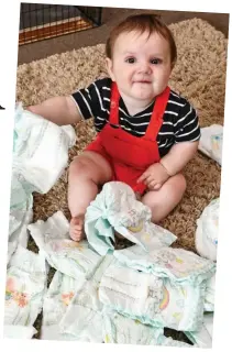  ??  ?? Full of joy: Archie, the youngest at eight months, rummages through a pile of nappies Pictures: BRUCE ADAMS