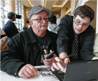  ?? Yi-Chin Lee / Houston Chronicle ?? Kyle Glaze, right, helps fellow job applicant Donald Bozeman fill out an electronic applicatio­n Saturday at RodeoHoust­on’s job fair. Organizers were looking to fill nearly 2,000 positions.