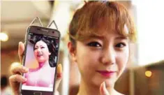  ??  ?? Hong Hye-Jin (So-Ah), a member of K-pop group SixBomb, with a photo of herself before her plastic surgery.