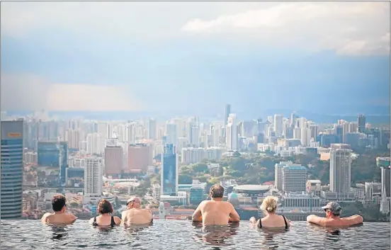  ?? GETTY ?? Huéspedes del Marina Bay Sands contemplan el perfil de Singapur desde la piscina del hotel