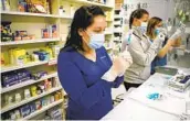  ?? DAVID ZALUBOWSKI ?? Pharmacist Claudia Corona-guevara joins nurses preparing shots of COVID-19 vaccine in Denver.