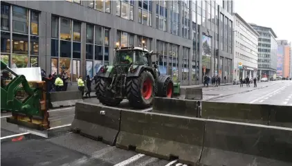  ?? Photo: Harry Nakos/AP ?? A tractor pushes through a concrete roadblock during a farmers demonstrat­ion in the European Quarter outside a meeting of EU agricultur­e ministers in Brussels, last Monday. European Union agricultur­e ministers meet in Brussels Monday to discuss rapid and structural responses to the crisis situation facing the agricultur­al sector.