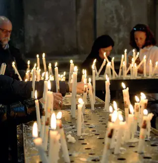  ??  ?? Offerte Pellegrini alla Madonna della Salute a Venezia mentre accendono candele