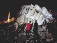  ??  ?? Palestinia­ns look on as they stand at the site where a building was destroyed by Israeli air strikes in Gaza City yesterday.