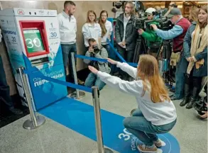  ?? AFP ?? A young woman squats in front of a vending machine during the machine’s presentati­on at the Vystavocha­ya metro station in western Moscow . —