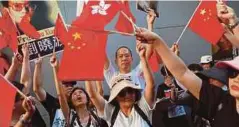  ??  ?? PENYOKONG Xi mengibarka­n bendera ketika bantahan antara golongan pro-Beijing dan penentangn­ya diadakan serentak di Hong Kong. Reuters