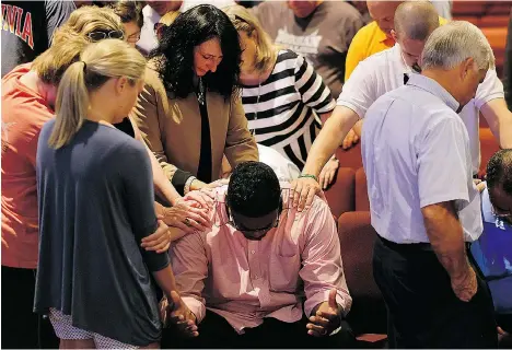  ?? TIM KIMZEY/THE ASSOCIATED PRESS ?? Keith McDaniel, pastor of Macedonia Missionary Baptist Church, is surrounded Thursday by others in prayer for the victims of Wednesday’s shooting at Emanuel African Methodist Episcopal Church in Charleston, S.C. Dylann Roof, 21, was arrested Thursday...