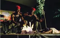  ?? — AFP photos ?? Actors play two red berret soldiers celebratin­g the burning of a young child they had snatched from her mother on May 30, 2018, in Harare, in a scene from a play “1983 the Dark Years”.