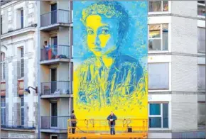  ?? AFP ?? French street artist and painter Christian Guemy (right), known as C215, poses in front of his fresco depicting a young Ukrainian girl.