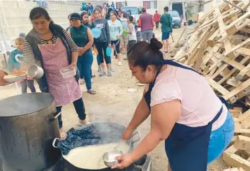  ?? ELLIOT SPAGAT/AP ?? A woman ladles rice and beans for a line of migrants last week at a shelter in Tijuana, Mexico.