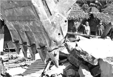  ?? — AFP photo ?? Two residents watch as workers destroy houses for security reasons after an earthquake hit the area of Gangga.