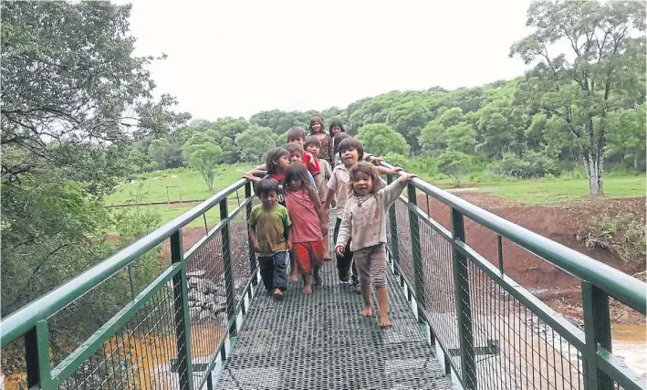  ?? CACIQUE VICENTE MENDEZ ?? Felices. Los chicos de la aldea mbya, el miércoles, caminan descalzos por la pasarela metálica de 52 metros que ahora los conecta con la escuela.