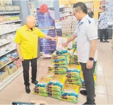  ?? ?? Ting (le ) and Ma hew check out bags of rice on sale at a special discounted rate throughout the two-day sales programme.