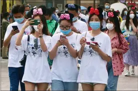  ?? SAM MCNEIL — THE ASSOCIATED PRESS ?? Visitors enter the Disneyland theme park in Shanghai as it reopened Monday. Visits will be limited initially and must be booked in advance, and the company said it will increase cleaning and require social distancing in lines for the various attraction­s.