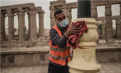 ??  ?? A municipali­ty worker cleans lamp posts amid a sandstorm and coronaviru­s fears outside the Luxor Temple in Egypt’s southern city of Luxor on 12 March. Photograph: Khaled Desouki/AFP via Getty Images