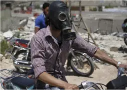  ?? (Abed Kontar/Reuters) ?? A MOTORCYCLI­ST in Syria, wearing a gas mask.