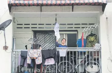  ??  ?? Single mother Tilda Kalaivani waves a shirt as a white flag to call for help, from her rental apartment in Kuala Lumpur.