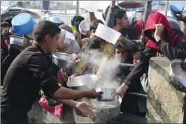  ?? HATEM ALI/ASSOCIATED PRESS ?? Palestinia­ns line up for food during the ongoing Israeli air and ground offensive on the Gaza Strip in Rafah on Tuesday.