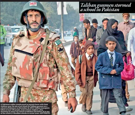  ??  ?? A Pakistani soldier stands guard as parents leave with their children near the site of an attack by Taliban gunmen on a school in Peshawar on December 16, 2014. Taliban insurgents killed at least 130 people, most of them children, after storming an...