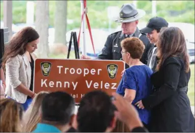  ?? ERIC BONZAR — THE MORNING JOURNAL ?? Family members of Ohio State Highway Patrol Trooper Kenneth Velez unveil a memorial highway plaque during a ceremony held in Lakewood on July 10.