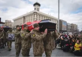  ?? AP PHOTO/EFREM LUKATSKY ?? People kneel Tuesday as servicemen carry the coffins of four Ukrainian soldiers during a commemorat­ion ceremony in Independen­ce Square in Kyiv, Ukraine.