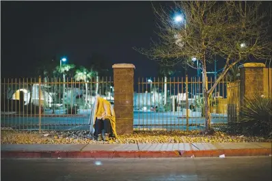  ?? WADE VANDERVORT ?? A homeless person sits alone under a blanket in the pre-dawn hours Feb. 24 near Catholic Charities at the corner of Foremaster Lane and Las Vegas Boulevard. Hundreds of other homeless people huddled in a group nearby.