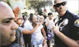  ??  ?? A WOMAN in the crowd that gathered outside the apartment complex yells at officers. “Obviously there are a lot of tensions here,” Police Capt. Steve Katz said.