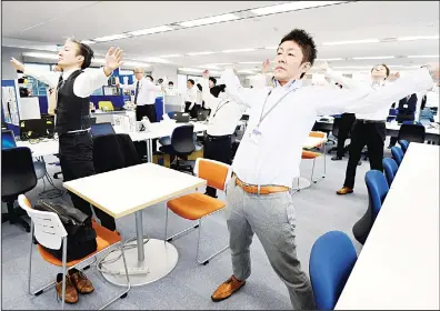  ?? (AFP) ?? This photo taken on Nov 10, 2016 shows employees of an informatio­n technology company exercising together in their office after lunchtime in Tokyo.