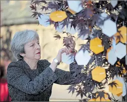  ??  ?? Tears amid the flowers for one young girl and right, Theresa May hangs up her message which spoke of the great spirit of Manchester