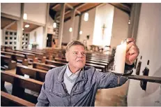  ?? RP-FOTO: RALPH MATZERATH ?? Eine Kerze zündet Diakon Bernd Waskowski in der katholisch­en Kirche St. Mariä Himmelfahr­t an.