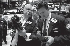  ?? AP/RICHARD DREW ?? Trader Thomas Ferrigno (left), speaks Friday with trader Glenn Kessler on the floor of the New York Stock Exchange. Stocks rose as investors reacted to a stronger-than-expected October jobs report.