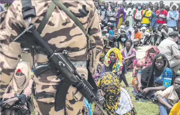  ??  ?? Beim Staatsbegr­äbnis für den verstorben­en Präsidente­n Idriss Déby in N’Djamena steht ein Soldat Wache vor Trauergäst­en, die in eine unsichere Zukunft zu blicken scheinen.