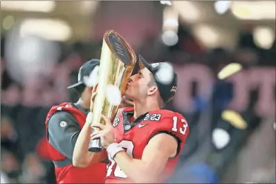  ?? Zachery C. Kelly ?? Georgia quarterbac­k Stetson Bennett kisses the College Football Playoff championsh­ip trophy after a victory over TCU on Monday.