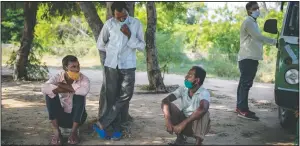  ?? (AP/Altaf Qadri) ?? Migrant workers Ram Ratanm(center standing) and Mansoor Ansari (seated right) talk sitting by the side of a road as they look for jobs in Manesar, India. “There is almost no work,” said Ratan, 46, who was working in a printing company before he returned to his home village in April.