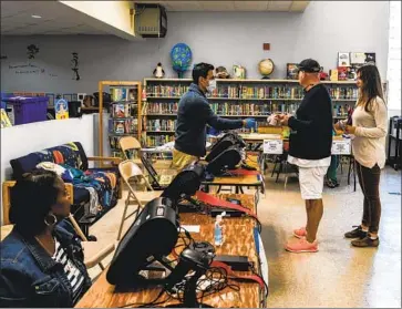  ?? Photograph­s by Chandan Khanna AFP/Getty Images ?? ELECTION WORKERS help Florida voters at a Miami Beach school. Primaries also took place in Arizona and Illinois, where some voters were told to stand 6 feet apart. Ohio’s vote was postponed at the last minute.