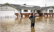  ?? ASSOCIATED PRESS ?? Colleen Kumada-mcgowan surveys the scene while standing in flood waters from huge amounts of rain in front of her home near San Francisco.