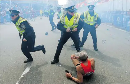  ?? JOHN TLUMACKI / AP/ THE BOSTON GLOBE ?? Bill Iffrig, 78, lies on the ground as police officers react to a second explosion at the finish line of the Boston Marathon on Monday. Iffrig, of Lake Stevens, Wash., was running his third Boston Marathon when he was knocked down by one of two bomb...