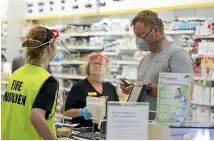  ?? STUFF ?? People wear protective gear at Life Pharmacy North City, Porirua. It is the only shop open at the mall.